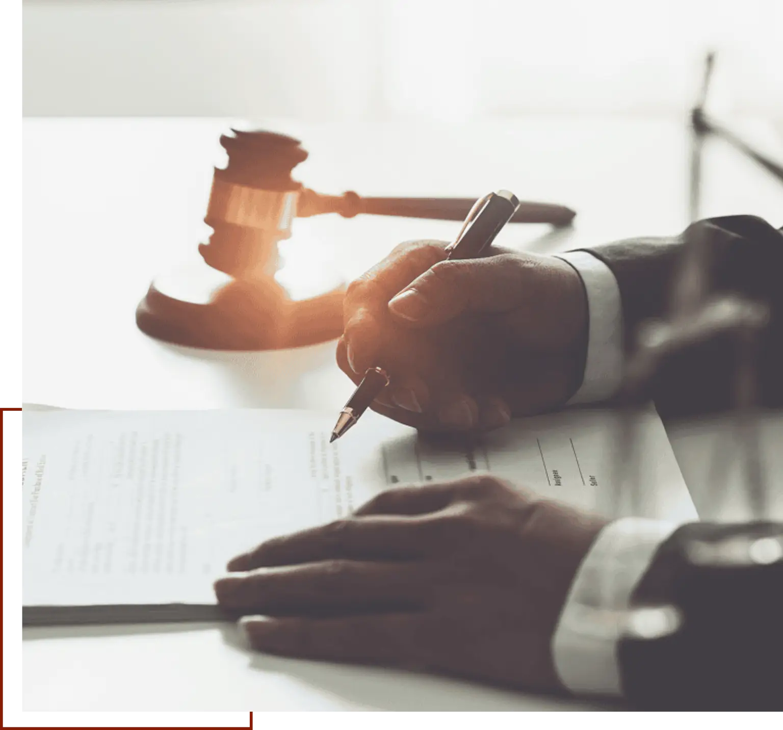 Man signing a contract with a gavel on top of a table