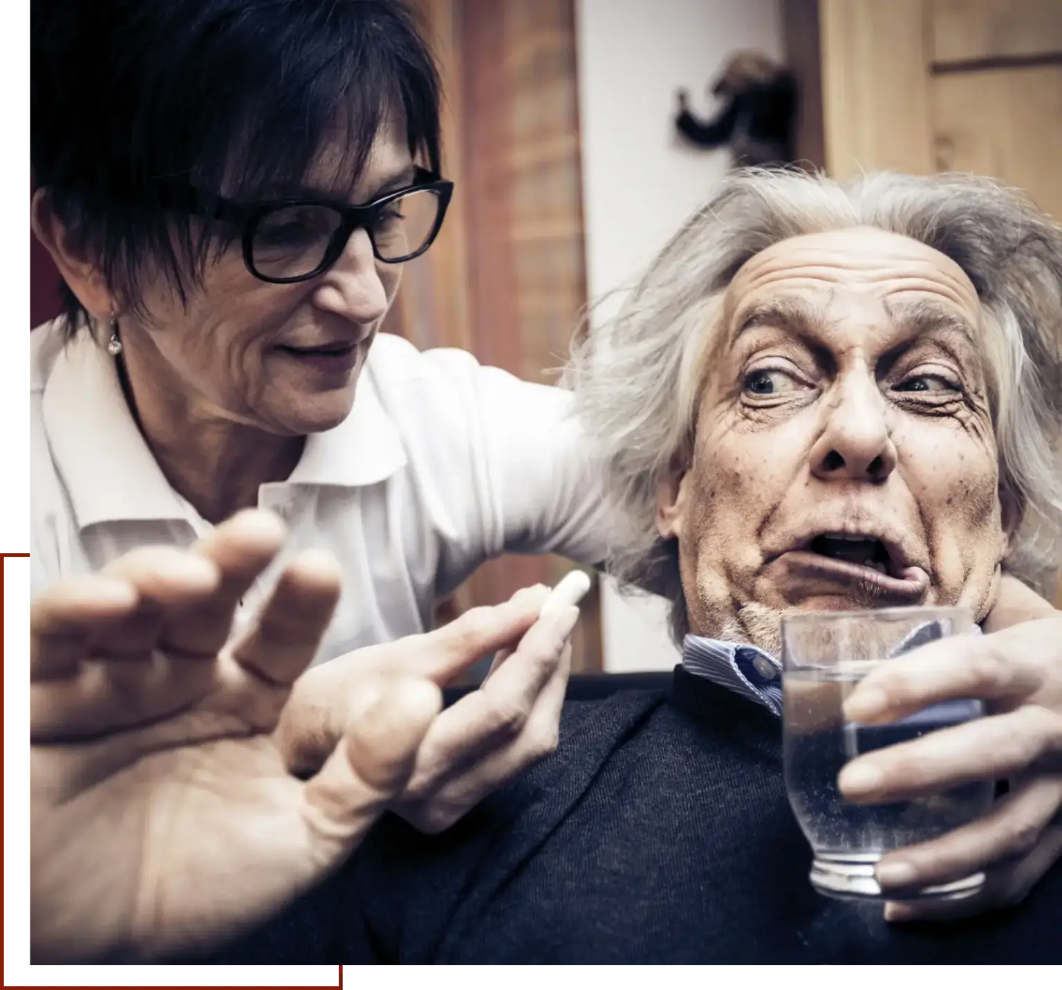 Older man and woman sitting at a table with a glass of water in the man's hand