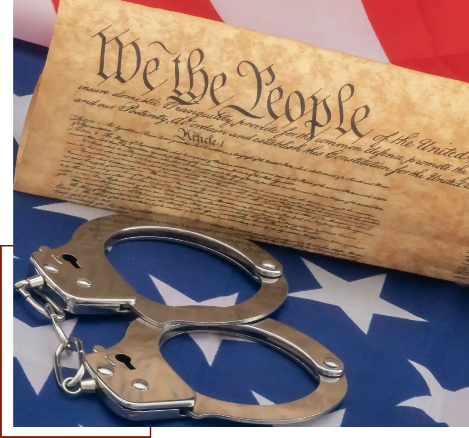 Pair of handcuffs sitting atop an American flag, with the text of the printed on the paper beneath them