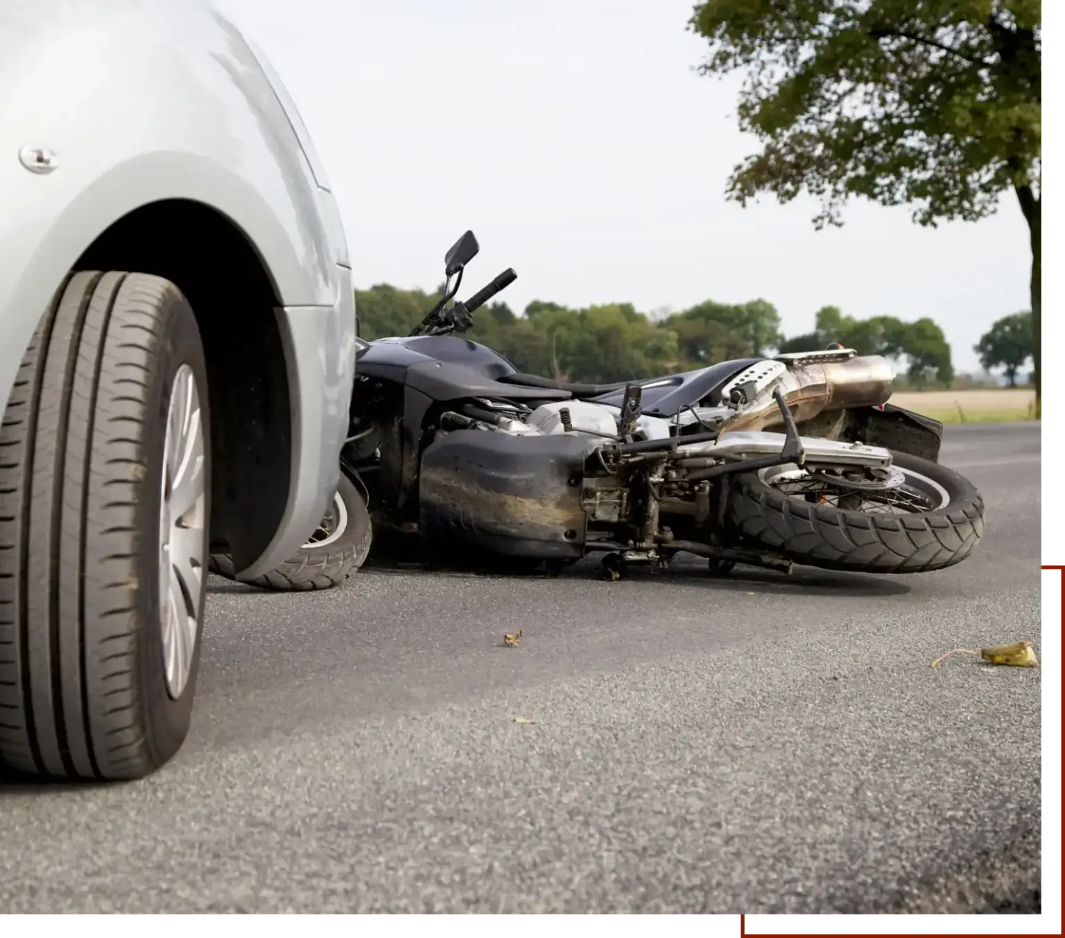 Motorcycle that has been involved in a car accident on the side of the road, surrounded by trees