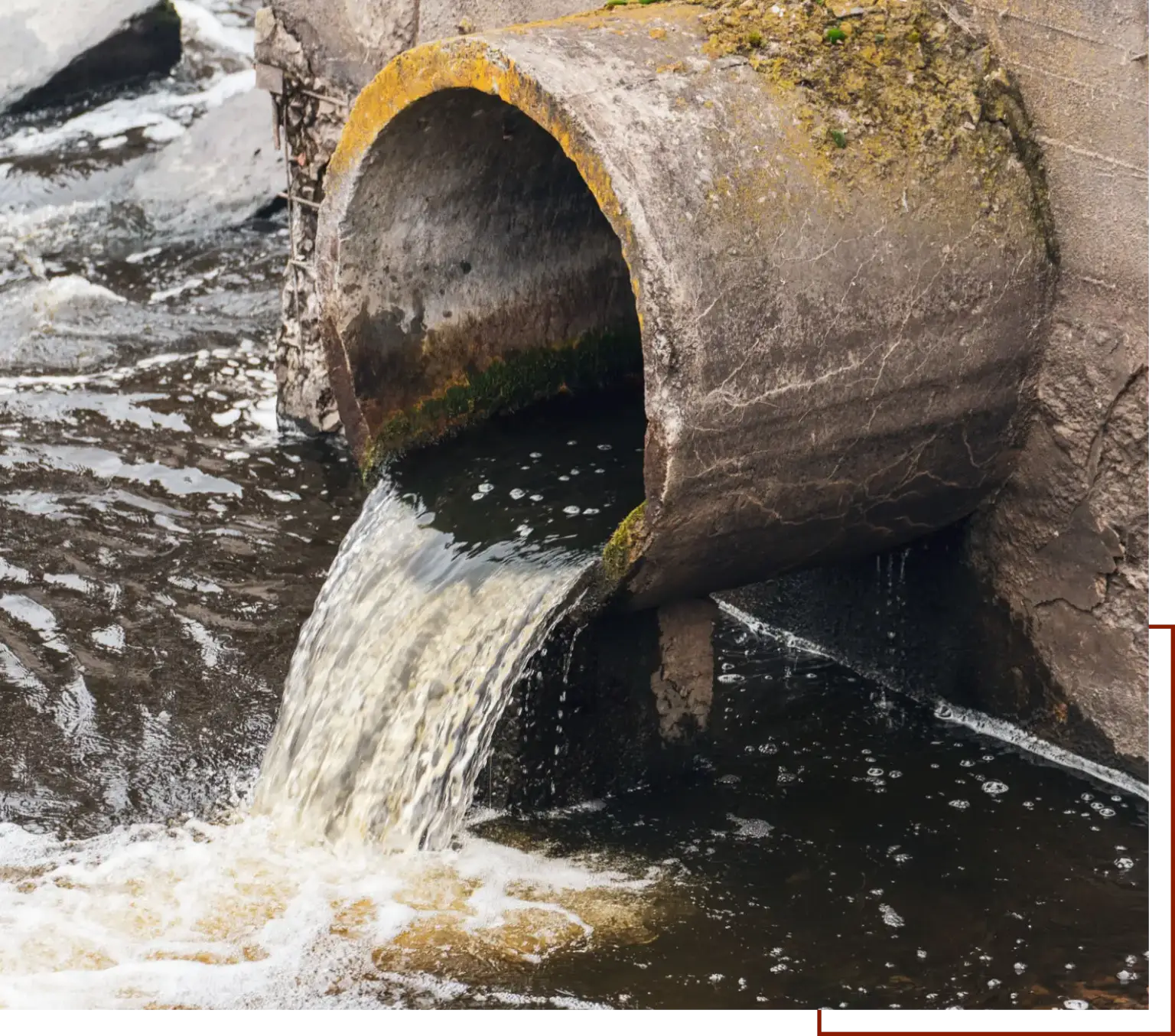 Pipe with water coming out of it, surrounded by rocks